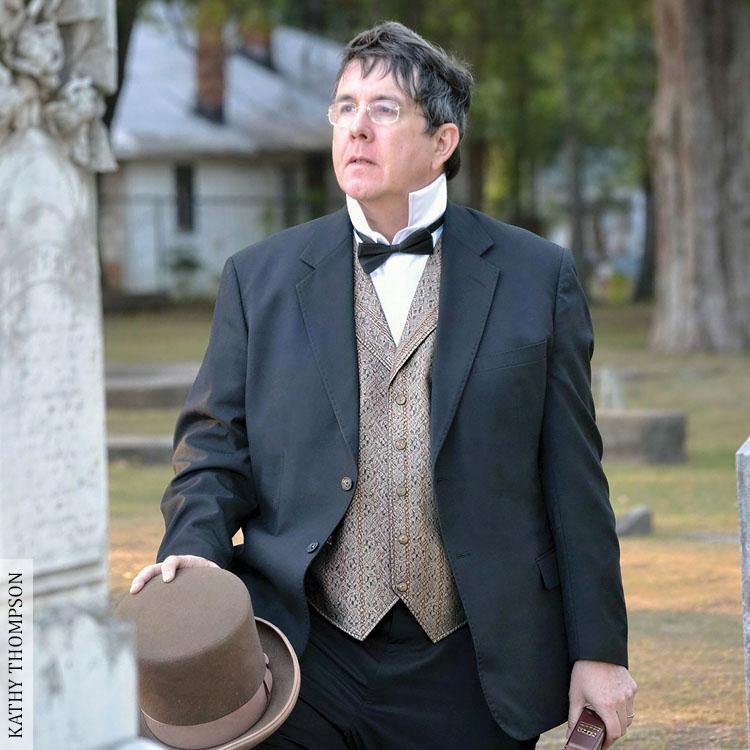 man standing by a tombstone
