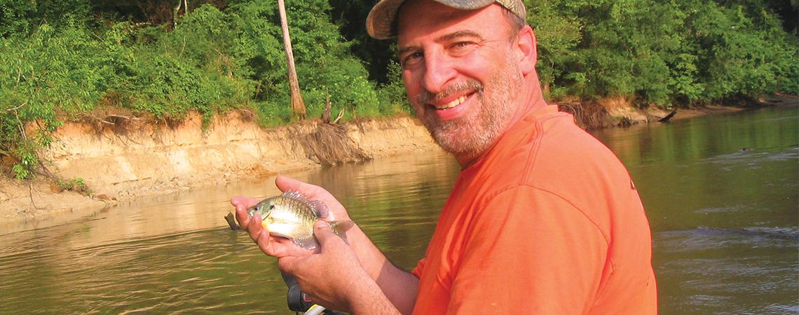 A fisherman shows off his catch of a small fish caught in a Georgia lake