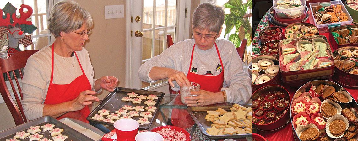 two women sit a table and shape cookies