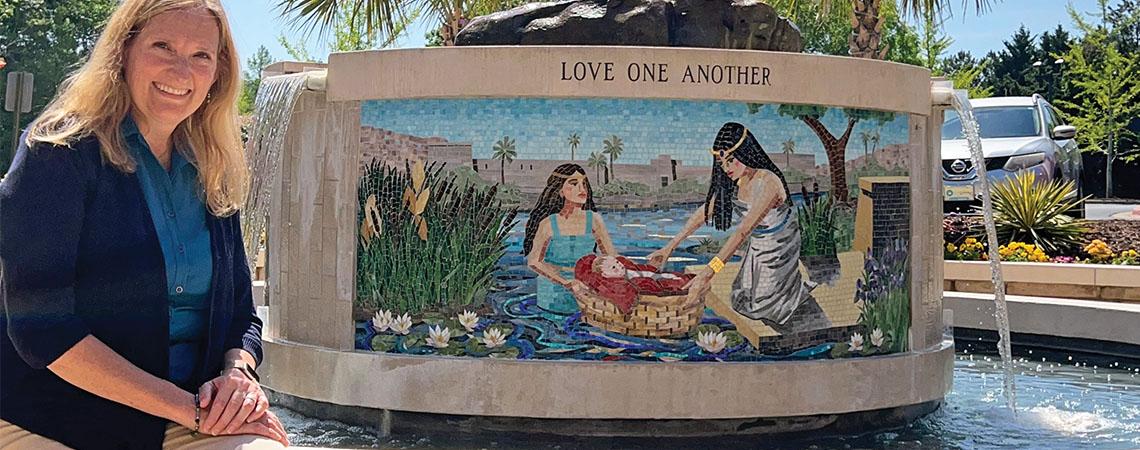 artist posing with mosaic fountain depicting the story of Moses