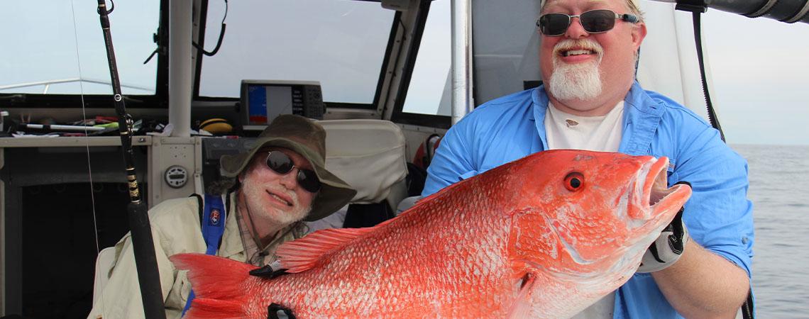 men holding large red snapper